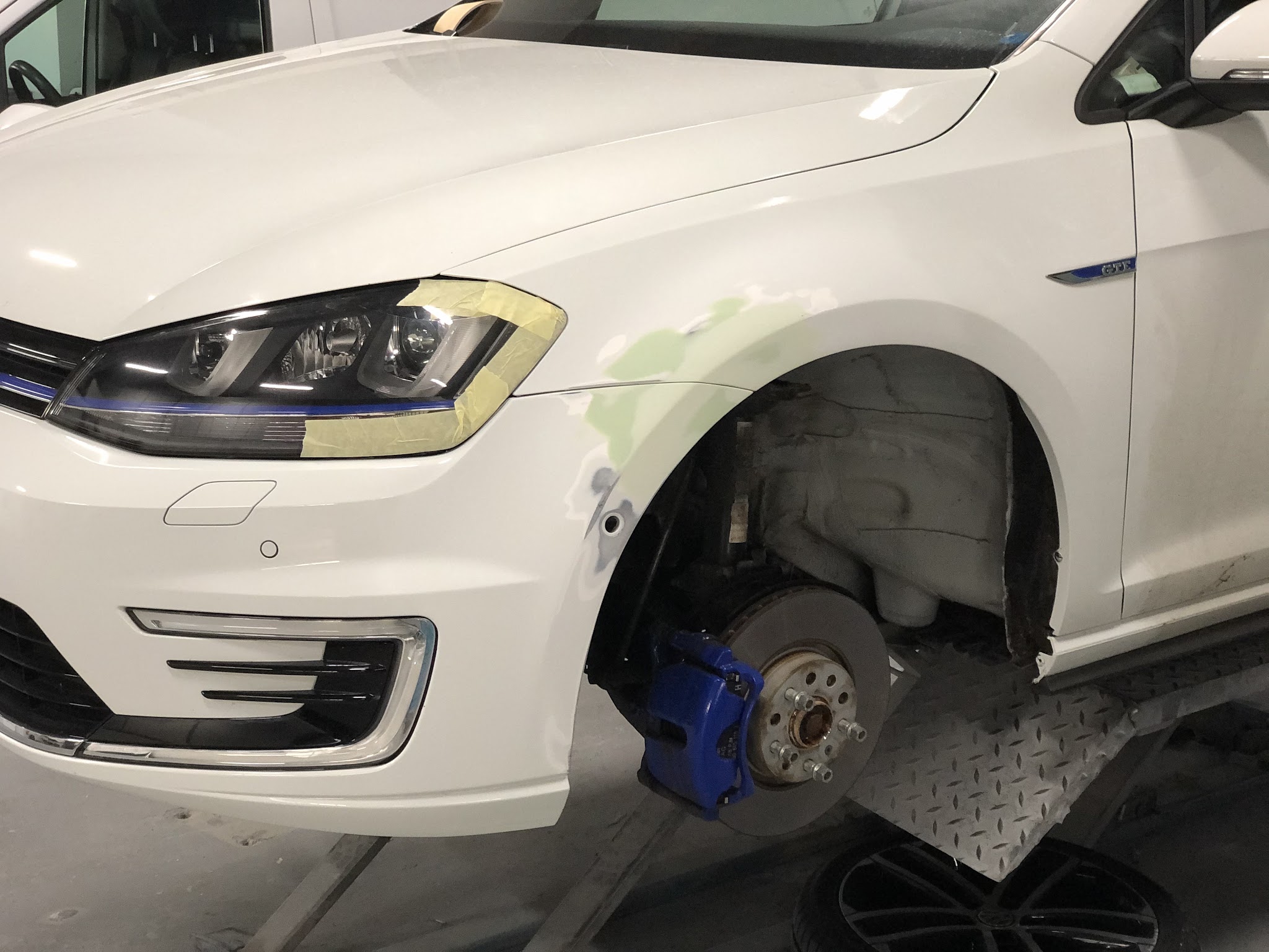 Witte Volkswagen Golf GTE met het voorscherm in bewerking en het wielhuis open