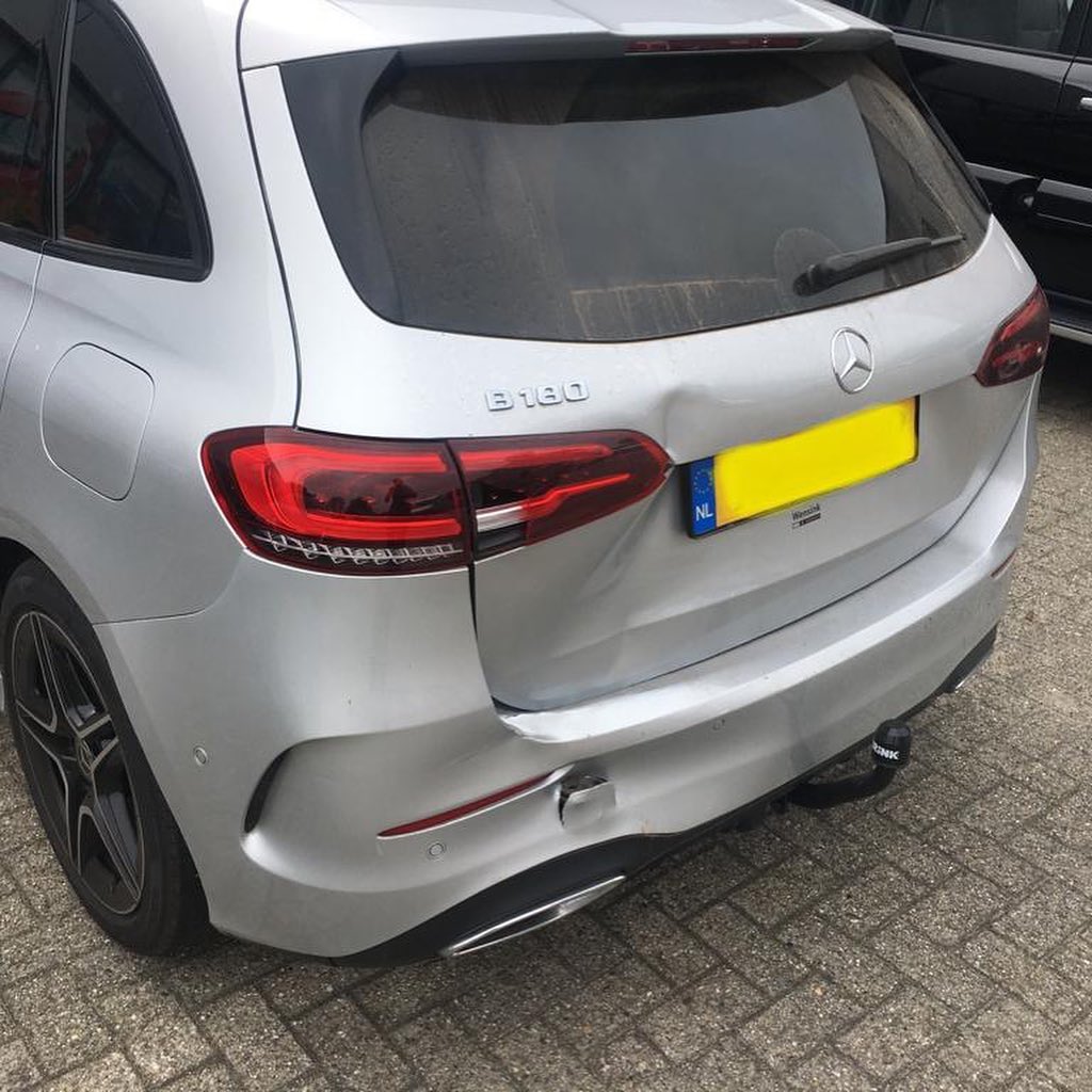 Zilveren Mercedes B180 met een deuk in de achterklep en bumper